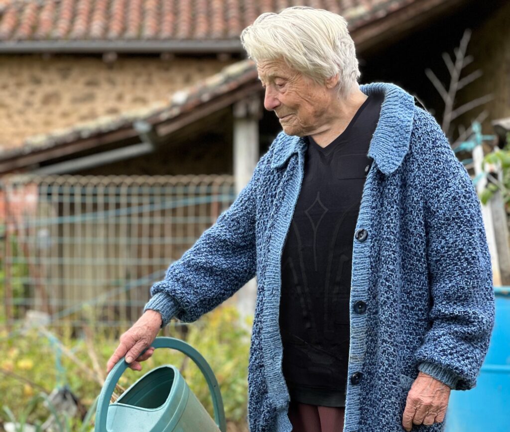 An elderly woman in her garden wearing our connected monitoring device