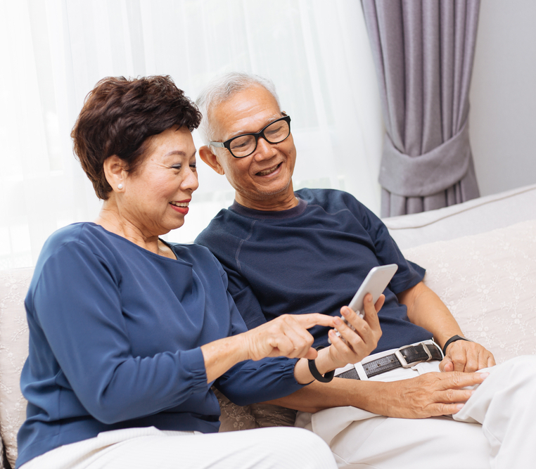 An elderly couple watching their smartphones on the sofa
